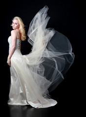 full length portrait of woman wearing white bridal gown. standing poison black studio background.