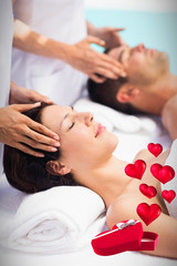 Obraz na płótnie Canvas Hearts flying from box against couple receiving head massage from masseur 3d