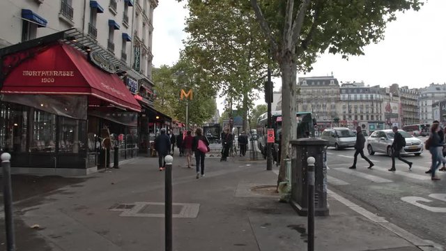PARIS, FRANCE - SEPTEMBER 29, 2017: Timelapse shot of walking on roadside sidewalk in busy city street. Passing by cafes and stores
