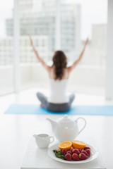 Woman sitting in meditation posture with healthy food in foreground