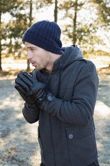 Man in warm clothing shivering while having a walk in forest