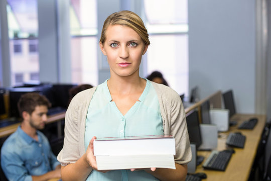 Female teacher holding books in computer class