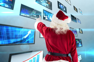Santa Claus points at something against screen collage showing business images - Powered by Adobe