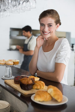 Confident cafe owner with sweet food at counter