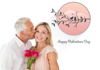 Affectionate man kissing his wife on the cheek with roses against cute valentines message