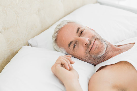 Closeup of a smiling mature man resting in bed