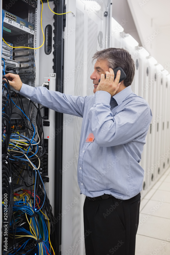 Poster Man fixing wires while making a phone call