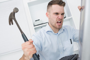 Frustrated man hitting computer monitor with hammer © WavebreakmediaMicro