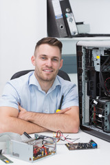 Smiling hardware professional sitting by an open cpu