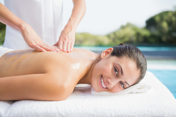 Happy brunette getting a massage poolside