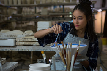 Female potter painting a bowl