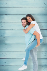 Happy casual man giving pretty girlfriend piggy back against wooden planks