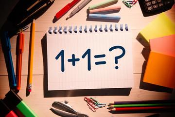 Composite image of one plus one against students desk