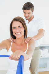 Male therapist assisting young woman with exercises