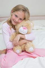 Young girl embracing stuffed toy in bed