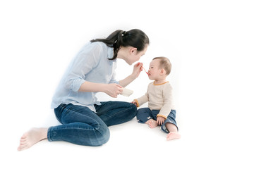 Mother is feeding the child with fruit mud, white background