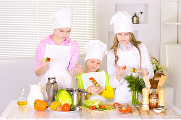 happy cute girls  cooking vegetable dish 