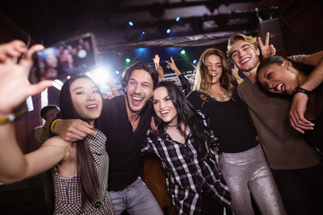Cheerful friends taking selfie while enjoying at nightclub
