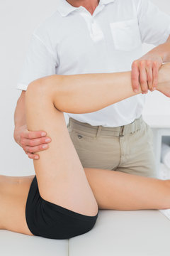 Male physiotherapist examining a young womans leg