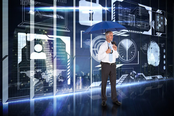 Happy businessman holding umbrella against hologram interface in office overlooking city