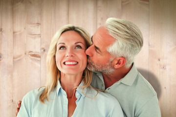 Affectionate man kissing his wife on the cheek  against wooden planks