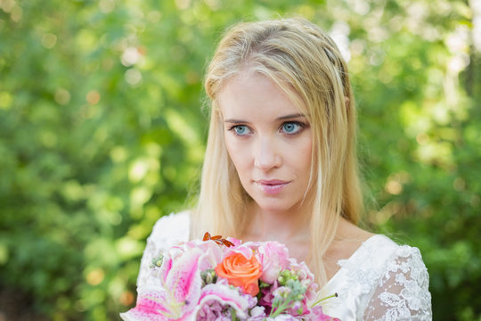 Blonde bride holding colourful bouquet looking away