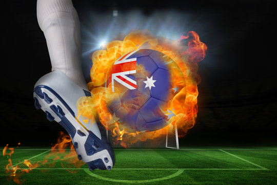 Football player kicking flaming australia flag ball against football pitch and goal under spotlights