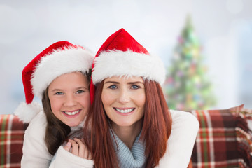 Mother and daughter against blurry christmas tree in room