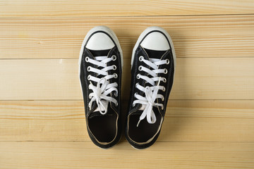 Top view of black canvas sneakers on wooden background