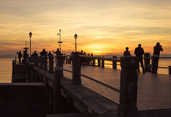 People enjoy sunset on pier in Sirmione, Garda lake, Italy.