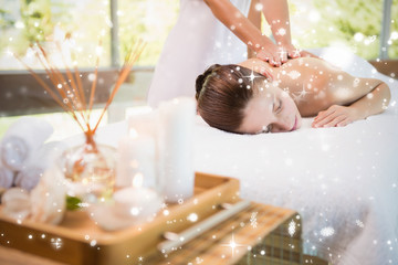 Attractive woman receiving back massage at spa center against snow falling