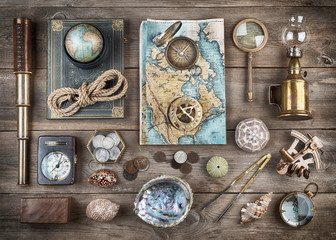 Exploration and nautical theme grunge background. Compass, telescope, sextant, divider, old coins, rope, shell, map, globe, magnifier, hourglass on wood desk. Retro style.