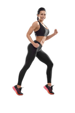 Photo of posing athletic female. Smiling woman with fit, curvy body doing sport exercises. Model having slim, stunning figure, wearing sport trousers and top, also sneackers for professional run. © serhiibobyk