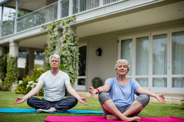 Senior couple practising yoga on exercise mat