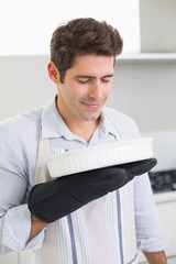 Fototapeta premium Man smelling food in baking dish in kitchen