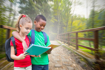Cute pupils reading against bridge with railings leading towards forest