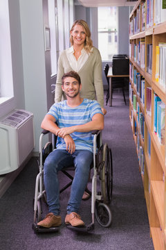 Smiling disabled student with classmate in library