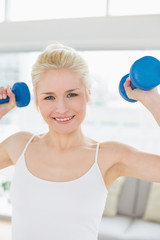 Smiling woman with dumbbells at fitness studio