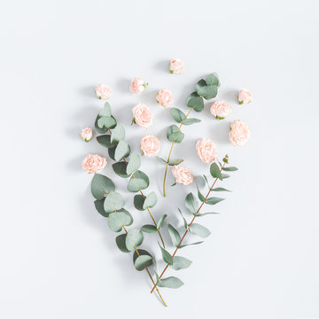 Flowers composition. Pattern made of rose flowers and eucalyptus branches on pastel blue background. Flat lay, top view, square