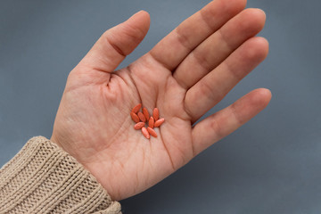 Female hand holds cucumber seeds. Orange grains for planting