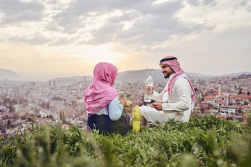 Arabic couple having a snack on the hill above a city