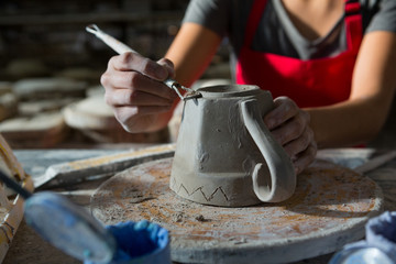 Fototapeta na wymiar Female potter carving mug
