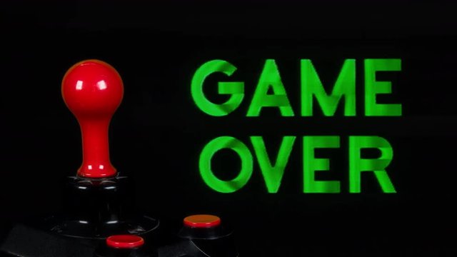 game over words from retro computer arcade with joystick spinning in the foreground