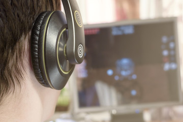 Boy with headphones looks to computer monitor