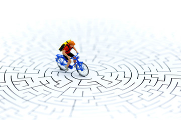 Miniature people : riding bicycle on start point of maze using as background business concept.