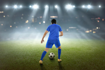 Obraz na płótnie Canvas Back view of asian footballer with the ball