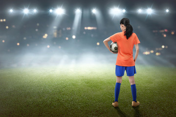 Rear view of asian female footballer with the ball