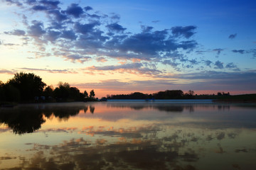 Morning over a lake in Poland, clouds are reflected in the surface of the water 