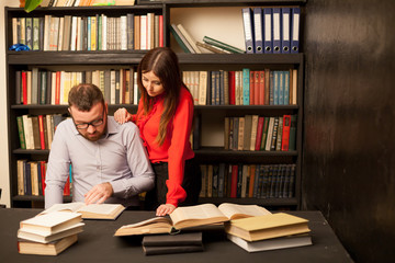 a man and a woman read books in the library are preparing for the exam