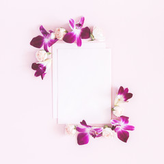 Flowers composition. Paper blank, orchid flowers on pastel pink background. Flat lay, top view, copy space, square